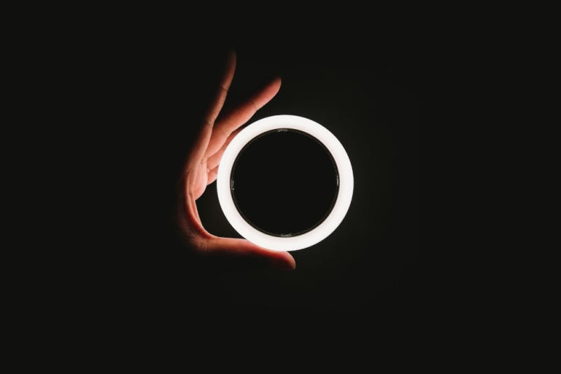 hand grasping glowing white ring on black background