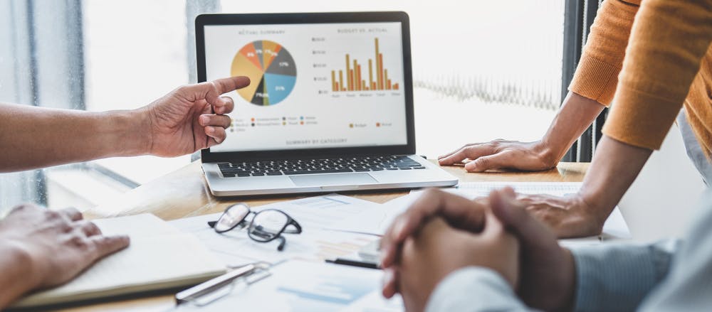 Stock photograph of data visualisation on a laptop screen with hands pointing to it.